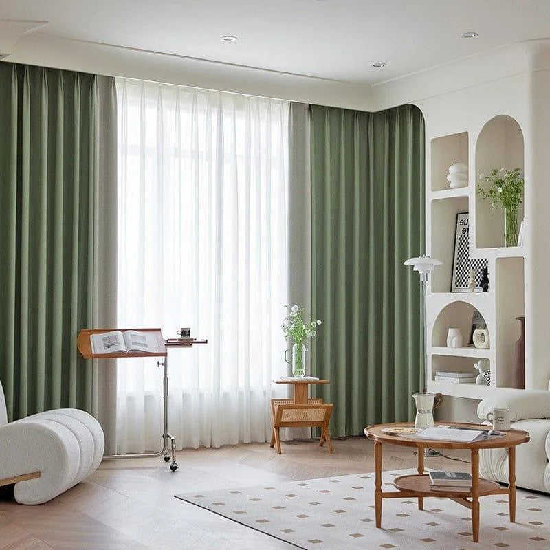 Salon moderne avec rideaux verts et décor minimaliste. Espace lumineux grâce à une grande fenêtre. Mobilier élégant comprenant une table basse en bois, étagères intégrées et fauteuil confortable. Parfait pour une ambiance chaleureuse et accueillante. Design intérieur contemporain avec touches de déco naturelle.