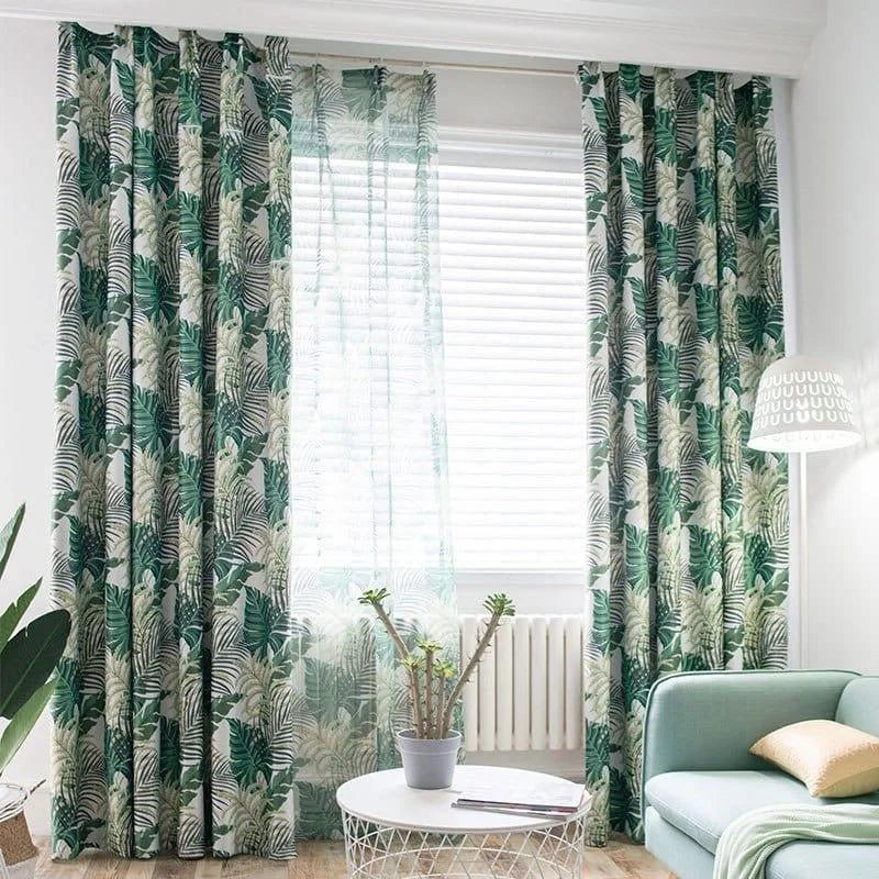 Rideaux à motif tropical vert et blanc égayant un salon moderne. Ces tentures ajoutent une touche de fraîcheur et d'élégance à la pièce, complétant un décor contemporain avec une lampe originale et un canapé confortable, tout en assurant un bel apport de lumière naturelle. Idéal pour créer une ambiance apaisante et chaleureuse dans votre intérieur.