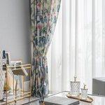Rideaux imprimés fleuris avec motifs tropicaux, ajoutant une touche élégante et rafraîchissante au salon moderne. Design chic parfait pour illuminer les espaces de vie contemporains avec une décoration intérieure harmonieuse. Accessoires dorés et table basse en verre complètent l'ambiance raffinée.