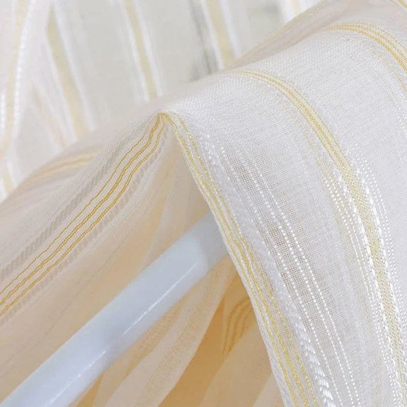 Voilage transparent avec rayures dorées élégant et moderne, parfait pour ajouter une touche de sophistication à votre intérieur. Idéal pour les fenêtres du salon, permettant d'apporter une lumière douce et naturelle à la pièce. Adapté à tous les styles de décoration grâce à son design épuré et raffiné.