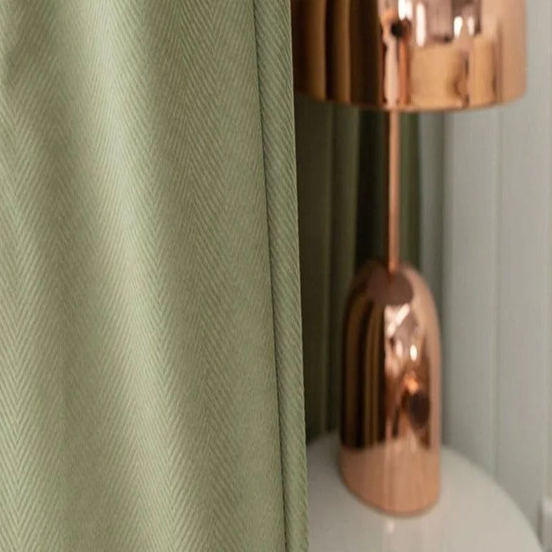 Rideau vert élégant avec motif chevron, parfait pour une décoration intérieure moderne. Lampe design en cuivre apportant une touche de sophistication à votre espace. Idéal pour créer une ambiance douce et contemporaine dans un salon ou une chambre. Accessoires tendance qui transforment instantanément votre intérieur.