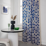 Rideau moderne à motifs circulaires bleus dans un intérieur élégant. Ce rideau apporte une touche contemporaine et artistique à votre pièce, s'associant parfaitement avec des décorations de table design. Parfait pour ceux qui cherchent à ajouter du style et de la couleur à leur espace de vie.