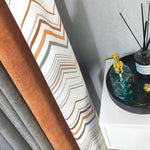 Rideau moderne avec motifs géométriques aux tons orange et gris, idéal pour embellir votre intérieur. Ce rideau apporte une touche d'élégance contemporaine à votre salon ou chambre. En second plan, un distributeur de savon élégant sur un plateau chic complète ce décor raffiné. Parfait pour un style moderne.