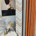 Rideaux élégants dans un salon moderne avec motif géométrique distinctif en orange, gris et blanc. Mettant en avant une ambiance artistique, ils sont accompagnés d'une statue décorative et d'un tableau raffiné, ajoutant une touche de sophistication à l'espace intérieur. Idéal pour rehausser la décoration intérieure contemporaine d'une maison.