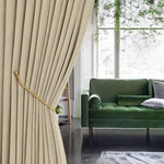 Rideau beige élégant pour salon moderne, offrant une ambiance chaleureuse et accueillante. Parfait pour ajouter une touche de sophistication à votre décoration intérieure. En arrière-plan, un canapé vert apporte une note de couleur tendance. Idéal pour créer un espace convivial et harmonieux.