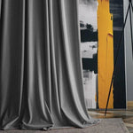 Rideau gris élégant drapé devant une œuvre d'art moderne avec des motifs jaunes et noirs, ajoutant une touche sophistiquée à la décoration intérieure. Idéal pour un salon ou une chambre contemporaine, combinant esthétique et fonctionnalité.