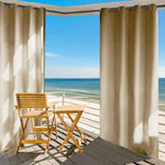 Rideaux extérieurs beige sur terrasse avec vue panoramique sur la mer, créant un espace détente élégant avec chaise et table en bois pour profiter du plein air et du paysage côtier. Idéal pour une ambiance apaisante en bord de mer.