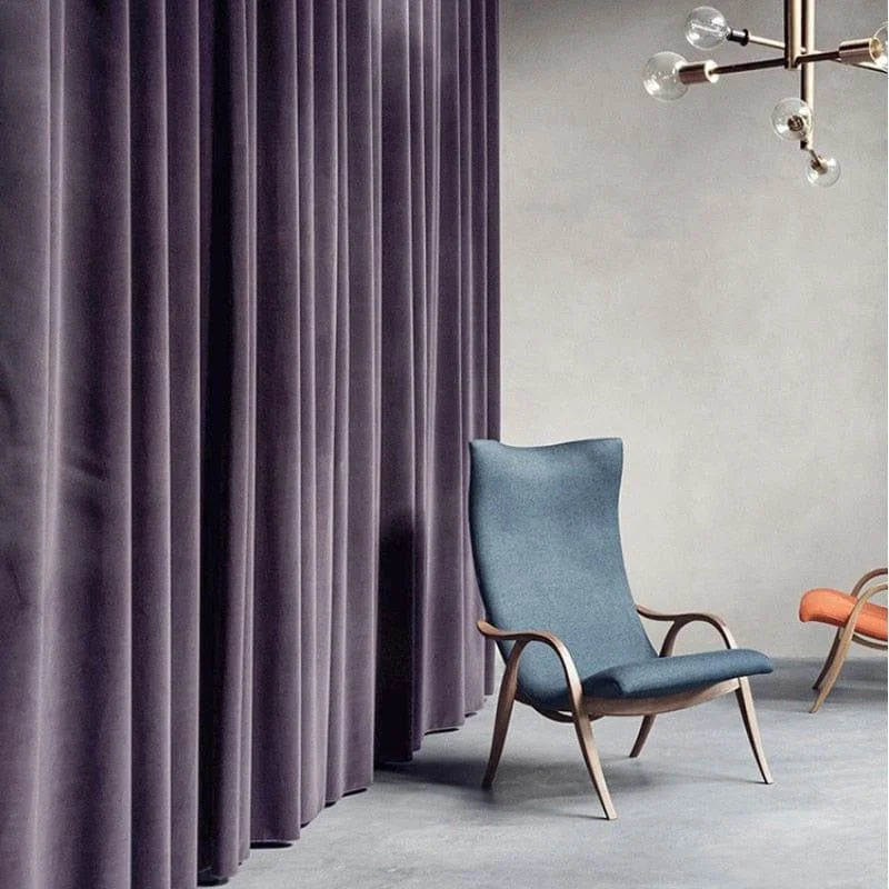 Fauteuil de design moderne au style scandinave dans un salon élégant, avec des rideaux de couleur sombre et un sol en béton, idéal pour une décoration intérieure contemporaine et sophistiquée.