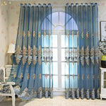 Rideaux bleu translucide avec motifs brodés dorés, ajoutant une touche élégante à une fenêtre de salon. Idéal pour filtrer la lumière tout en préservant l'intimité. Design raffiné et décoration sophistiquée pour un intérieur contemporain. Convient parfaitement pour une atmosphère chaleureuse et accueillante.