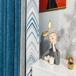 Voilage contemporain en teintes de bleu et gris, accompagné d'une statuette décorative moderne devant un mur au design géométrique. Parfait pour un style intérieur élégant et unique. Transformez votre espace avec cette combinaison d'éléments décoratifs raffinés.