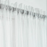 Voilage blanc délicat avec plis ondulés pour habillage de fenêtre, offrant une atmosphère lumineuse et élégante. Accessoire idéal pour une décoration intérieure moderne et épurée, parfait pour ajouter une touche de légèreté à n'importe quelle pièce.