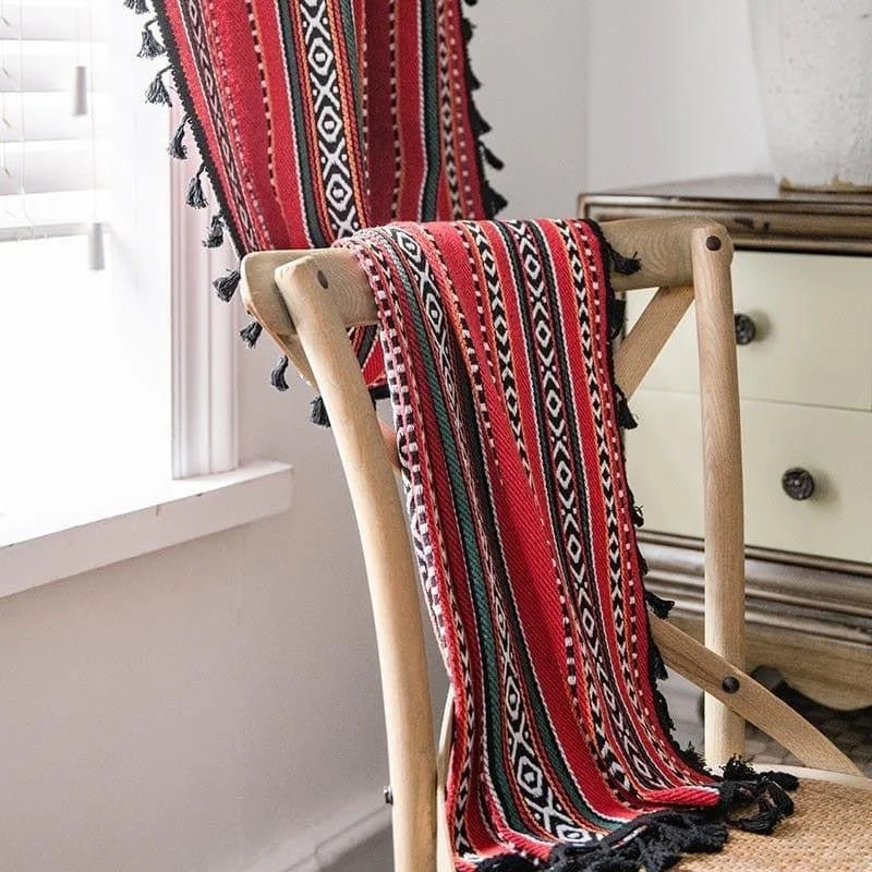 Tissu d'ameublement décoratif aux motifs traditionnels géométriques rouges et noirs, idéal pour ajouter une touche de couleur et d'originalité à votre intérieur, présenté sur une chaise en bois dans une pièce lumineuse.