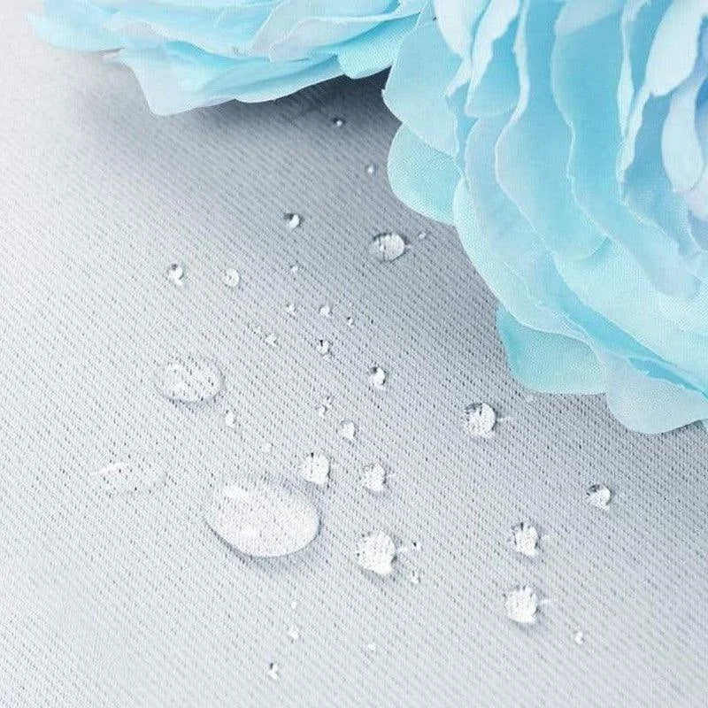 Gouttelettes d'eau perlant sur une surface imperméable avec des fleurs décoratives bleues, démontrant la résistance à l'humidité et l'élégance du design.