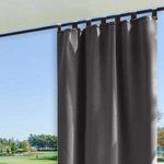 Rideau gris élégant suspendu devant une grande fenêtre avec vue sur jardin. Accessoire parfait pour améliorer la décoration intérieure et contrôler la luminosité de la pièce. Conception moderne adaptée à tous les types de fenêtres.