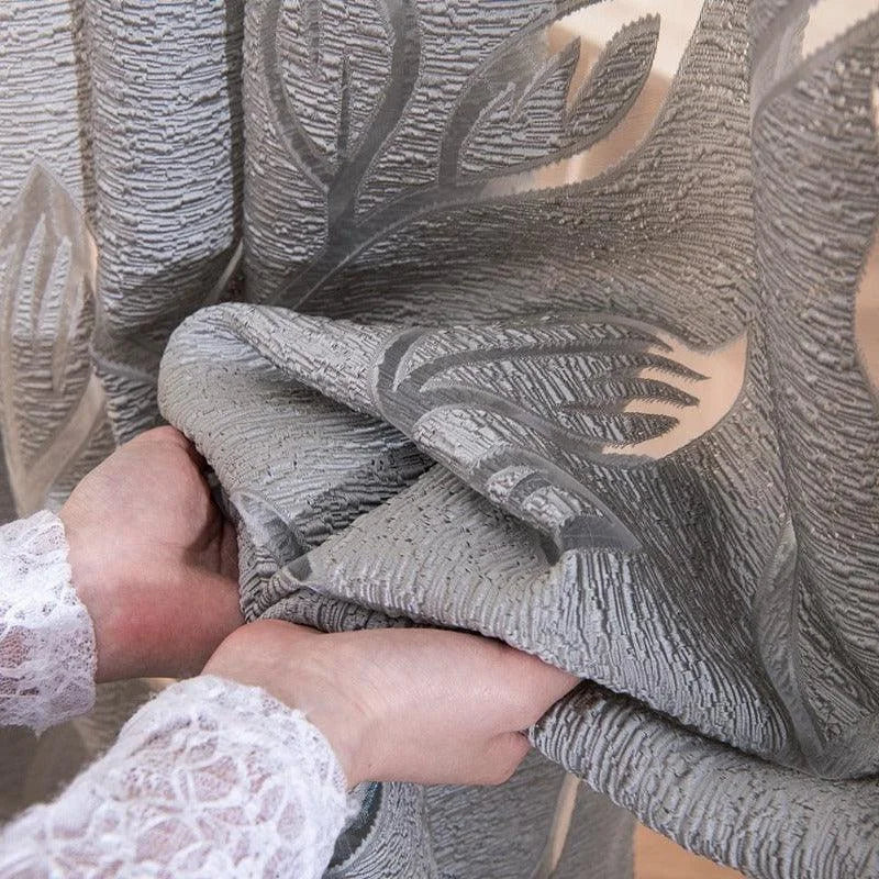 Voilage élégant aux motifs floraux en gris argenté, idéal pour embellir votre intérieur. Ce rideau décoratif apporte une touche de sophistication et d'intimité à votre espace de vie tout en laissant passer la lumière naturelle. Parfait pour salon, chambre ou bureau.