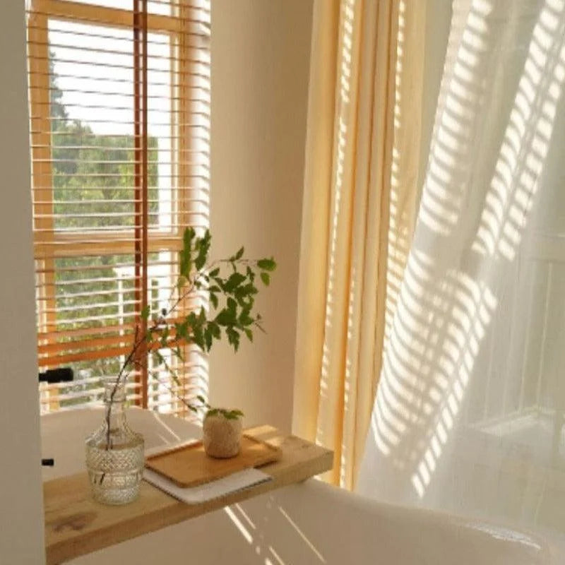 Décoration intérieure avec une étagère minimaliste près de la fenêtre, ornée d'un vase et d'une plante, baignée de lumière naturelle.