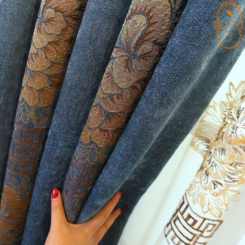 Rideau en tissu bleu avec motifs floraux dorés, design élégant pour salon ou chambre, intérieur moderne et chic, main ajustant le rideau.