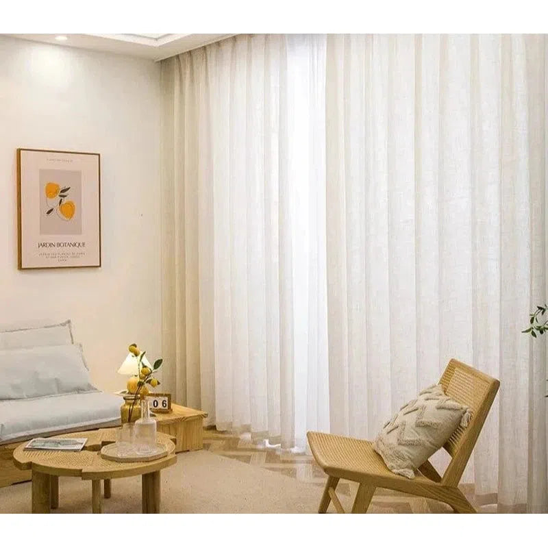 Salon moderne avec rideaux blancs élégants, design épuré et mobilier en bois clair, créant une ambiance lumineuse et accueillante. Décoration minimaliste avec une chaise confortable, une table basse et un tableau artistique. Idéal pour un intérieur contemporain et chaleureux.