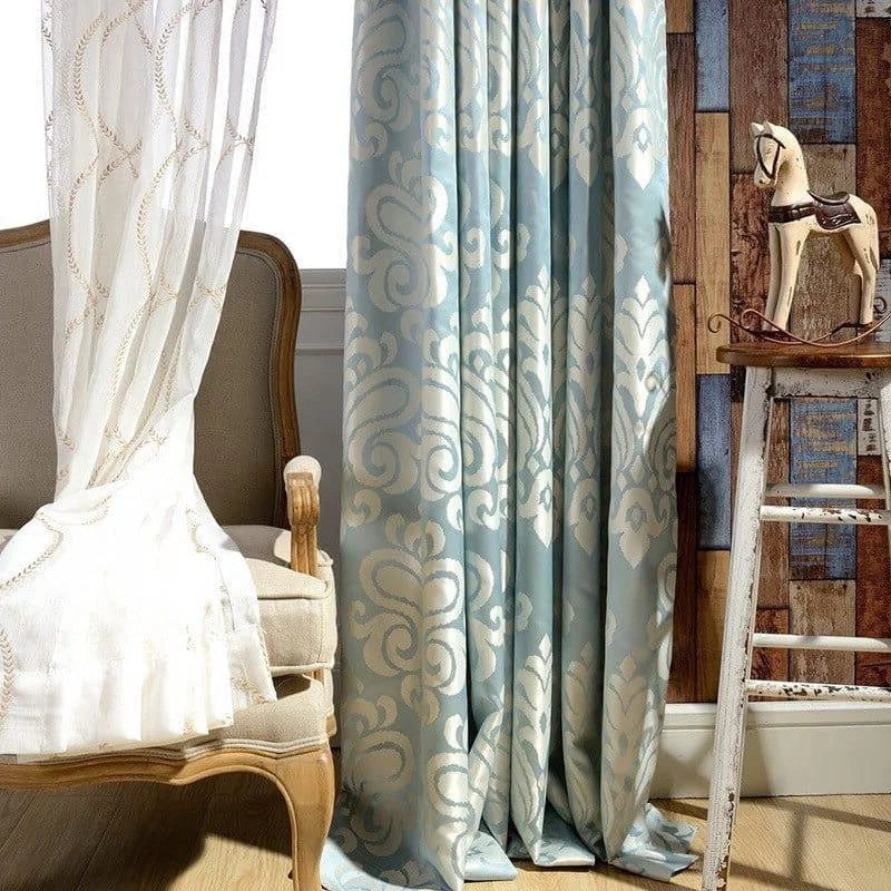 Rideaux élégants avec motifs baroques en bleu et beige, idéals pour apporter une touche de sophistication à votre salon. Parfaits pour une décoration intérieure chaleureuse et accueillante, ils complètent un espace classique avec une chaise vintage et une ambiance rétro. Accessoire de choix pour rehausser l'esthétique de votre maison et filtrer la lumière avec style.