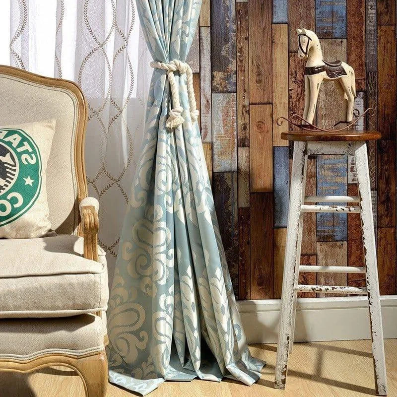 Rideau bleu à motifs élégants dans un salon au design vintage, avec un cheval en bois sur tabouret et un fauteuil confortable. Ambiance chaleureuse et esthétique raffinée pour une décoration intérieure chic.