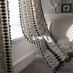Rideau bohème chic avec motifs géométriques noirs et blancs, parfait pour embellir un salon moderne. Ses franges élégantes ajoutent une touche d'originalité à la décoration intérieure. Idéal pour filtrer la lumière tout en créant une ambiance apaisante et stylée.