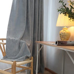 Rideau à motifs chevrons gris et blancs, suspendu dans un intérieur élégant. Il encadre harmonieusement une fenêtre, ajoutant sophistication et style. Parfait pour créer une ambiance chaleureuse et accueillante, tout en offrant une intimité optimale pour tout type d'intérieur moderne.