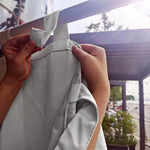Personne accrochant un rideau occultant gris sur une tringle extérieure, idéal pour offrir une protection solaire sur une terrasse ou un balcon tout en préservant l’intimité. Le design pratique avec des attaches faciles garantit une installation rapide et sans effort. Parfait pour embellir votre espace extérieur tout en ajoutant une touche fonctionnelle.