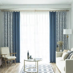 Rideaux élégants combinant des teintes bleues et motifs géométriques pour un salon moderne et lumineux. Ces tentures décoratives contrastent harmonieusement avec un mobilier minimaliste, apportant une touche de sophistication à l'espace de vie. Idéal pour créer une ambiance chic et accueillante.