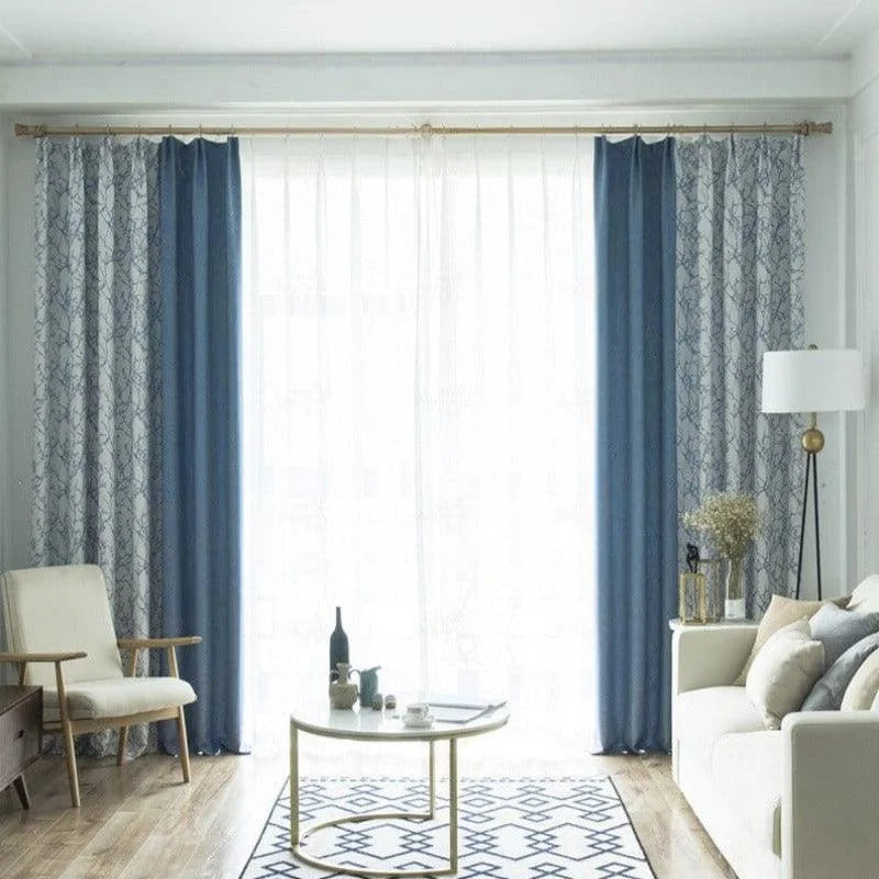 Rideaux élégants combinant des teintes bleues et motifs géométriques pour un salon moderne et lumineux. Ces tentures décoratives contrastent harmonieusement avec un mobilier minimaliste, apportant une touche de sophistication à l'espace de vie. Idéal pour créer une ambiance chic et accueillante.