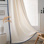 Rideau moderne de couleur beige avec bordure décorative bleue, idéal pour un salon contemporain. Apporte élégance et luminosité à votre intérieur grâce à son style épuré. Accessoire déco parfait pour créer une ambiance chaleureuse et accueillante dans votre maison.