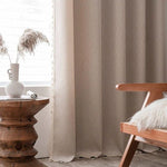 Rideaux élégants beige clair dans une décoration intérieure moderne avec une table d'appoint en bois sculpté. Le cadre chaleureux est enrichi par un fauteuil design et un vase déco, apportant une ambiance cosy et naturelle à votre salon. Parfaits pour filtrer la lumière tout en ajoutant une touche chic et accueillante à votre espace.