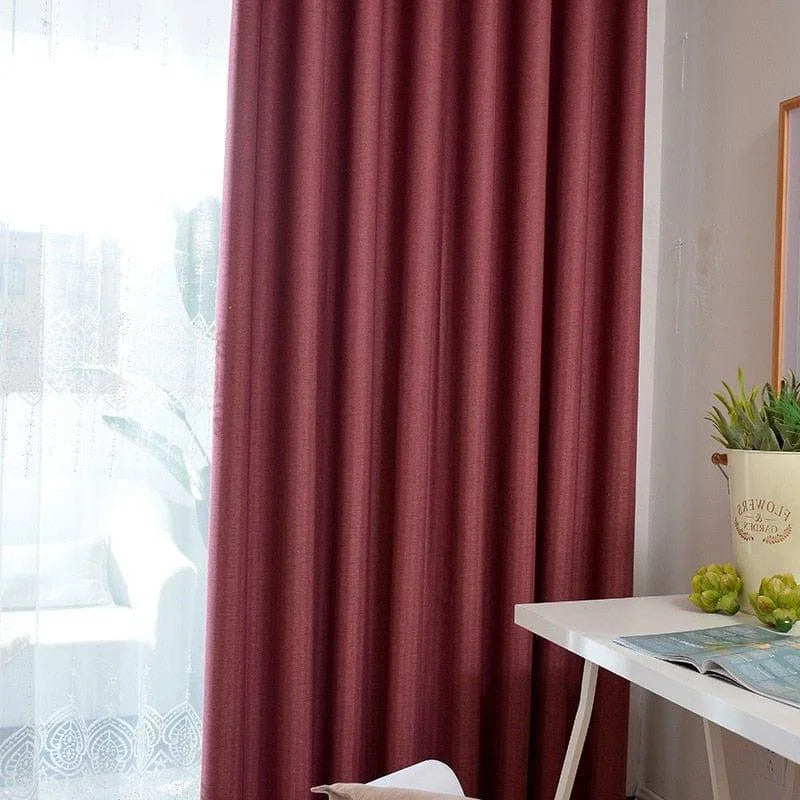Rideaux occultants rouges dans un salon lumineux avec table blanche et plante verte, apportant une touche moderne et chaleureuse à la décoration intérieure. Parfait pour contrôler la lumière et ajouter une élégance colorée à votre espace de vie.
