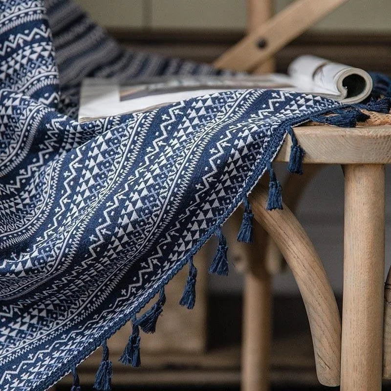 Tissu décoratif bleu et blanc avec motifs géométriques inspirés du design ethnique, idéal pour ajouter une touche de style traditionnel à votre intérieur. Plaid élégant disposé sur une chaise en bois, parfait pour une ambiance cosy et chaleureuse. Accessoire polyvalent pour personnaliser votre espace de vie.