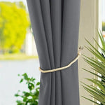 Rideau d'intérieur élégant gris pour salon moderne, attaché avec une corde décorative beige, offrant une ambiance chaleureuse et raffinée à votre décoration. Vue sur un jardin luxuriant par la fenêtre, parfait pour filtrer la lumière tout en embellissant votre espace de vie. Accessoire idéal pour personnaliser votre intérieur.