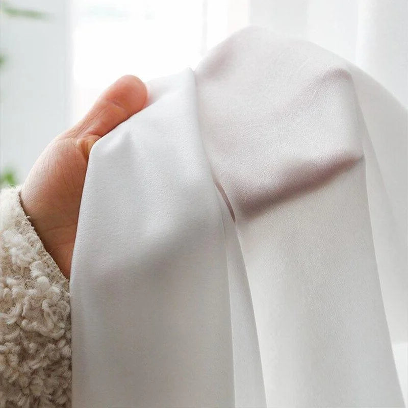 Voile blanc élégant, parfait pour des rideaux modernes ou une décoration intérieure raffinée. Lumière douce passant à travers, créant une ambiance chaleureuse et accueillante. Idéal pour ajouter une touche de sophistication à n'importe quelle pièce de la maison.