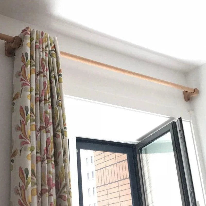 Tringle à rideaux élégante avec rideaux à motifs floraux, installée au-dessus d'une fenêtre ouverte, idéale pour une décoration intérieure moderne et chaleureuse.