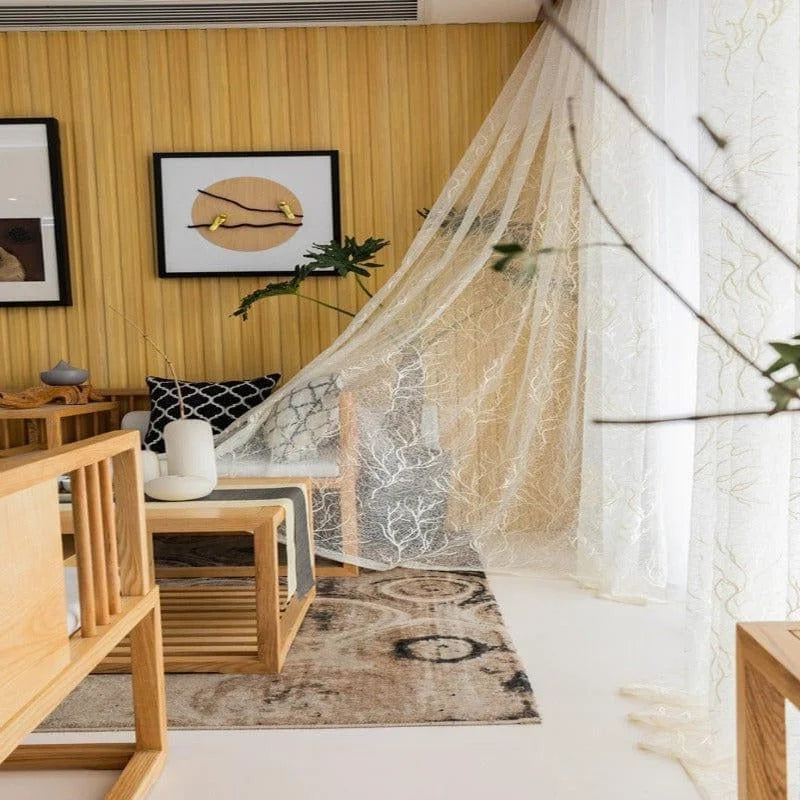 Salon moderne avec décoration minimaliste, mettant en valeur un rideau élégant et léger. Espaces lumineux et accueillants, accentués par des meubles en bois clair. Ambiance sereine idéale pour la détente et le bien-être, rehaussée par des éléments décoratifs harmonieux. Atmosphère chaleureuse et contemporaine pour un intérieur raffiné.