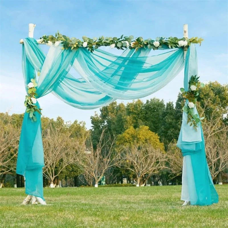 Arche de mariage élégante en plein air décorée de voilages turquoises et de fleurs blanches, idéale pour une cérémonie nuptiale en extérieur. Créez une ambiance romantique et naturelle dans un cadre verdoyant avec cette structure raffinée. Parfait pour les mariages, les événements mémorables ou les séances photo en plein air.