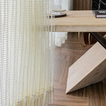 Rideau élégant blanc translucide avec motifs géométriques suspendu devant une table moderne en bois clair. Parfait pour apporter une ambiance lumineuse et contemporaine à votre intérieur. Idéal pour une salle à manger ou un salon, ce rideau ajoute une touche de style et de sophistication.