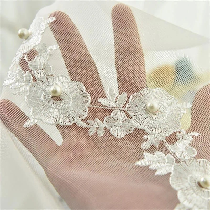 Voile délicat orné de fleurs brodées pour décoration de mariage. Élégance et raffinement assuré avec perles intégrées pour un style intemporel. Accessoire idéal pour personnaliser une robe ou des accessoires de cérémonie.