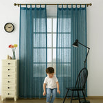 Voilage bleu translucide à motifs dorés installé dans une chambre d’enfant, avec un petit garçon au premier plan.
