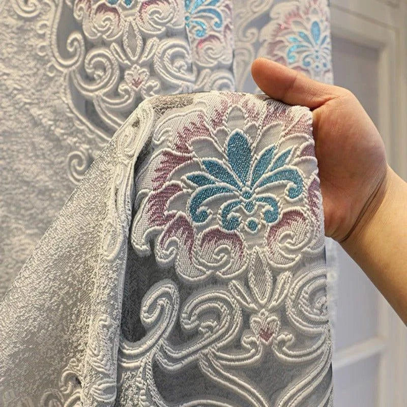 Rideau élégant avec motif floral en filigrane, accentué de nuances bleues et roses. Design classique et raffiné idéal pour embellir un salon ou une chambre. Parfait pour ajouter une touche de sophistication à votre décoration intérieure.