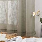 Voilage translucide beige suspendu, offrant une touche élégante et moderne à la décoration intérieure. La lumière douce filtrant à travers le tissu crée une ambiance chaleureuse. Parfait pour le salon ou la chambre, ce rideau s'accompagne d'une tasse de café et d'un livre, suggérant un espace de détente et de lecture. Un vase avec des fleurs fraîches ajoute une note naturelle et apaisante à l'ensemble.