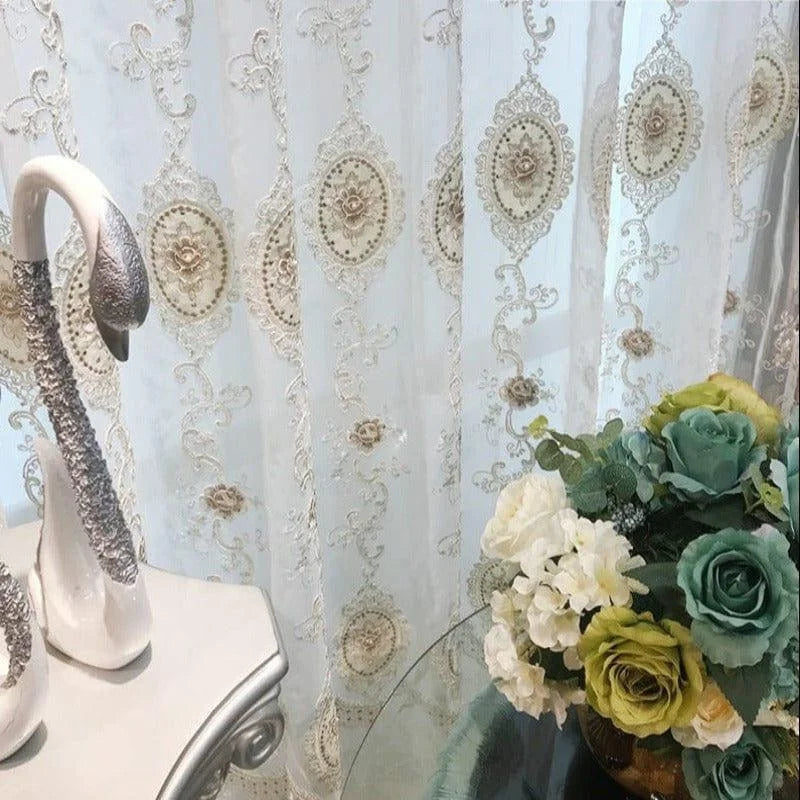 Rideaux élégants avec motifs floraux brodés, ajoutant une touche chic à votre intérieur. Décoration idéale pour salon ou chambre. Vase avec fleurs colorées sur une table moderne, accentuant le style sophistiqué de la pièce. Accessoires décoratifs raffinés pour un espace accueillant et harmonieux.
