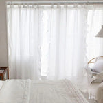 Rideaux blancs translucides élégants suspendus devant une baie vitrée dans une chambre lumineuse. Design contemporain, idéal pour ajouter une touche de légèreté et d'intimité à n'importe quel espace de vie. Convient parfaitement pour une ambiance douce et apaisante.
