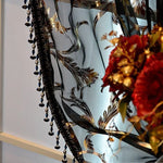 Rideau décoratif avec motifs floraux noirs et dorés, agrémenté de perles suspendues, idéal pour ajouter une touche d'élégance et de sophistication à votre intérieur. Les motifs raffinés fusionnent harmonieusement avec un joli bouquet de fleurs rouges, créant une ambiance chaleureuse et luxueuse dans la pièce. Parfait pour embellir salons et chambres avec style et charme.