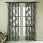 Rideaux gris à motifs géométriques suspendus devant une grande fenêtre, apportant une touche élégante et moderne à la décoration intérieure.
