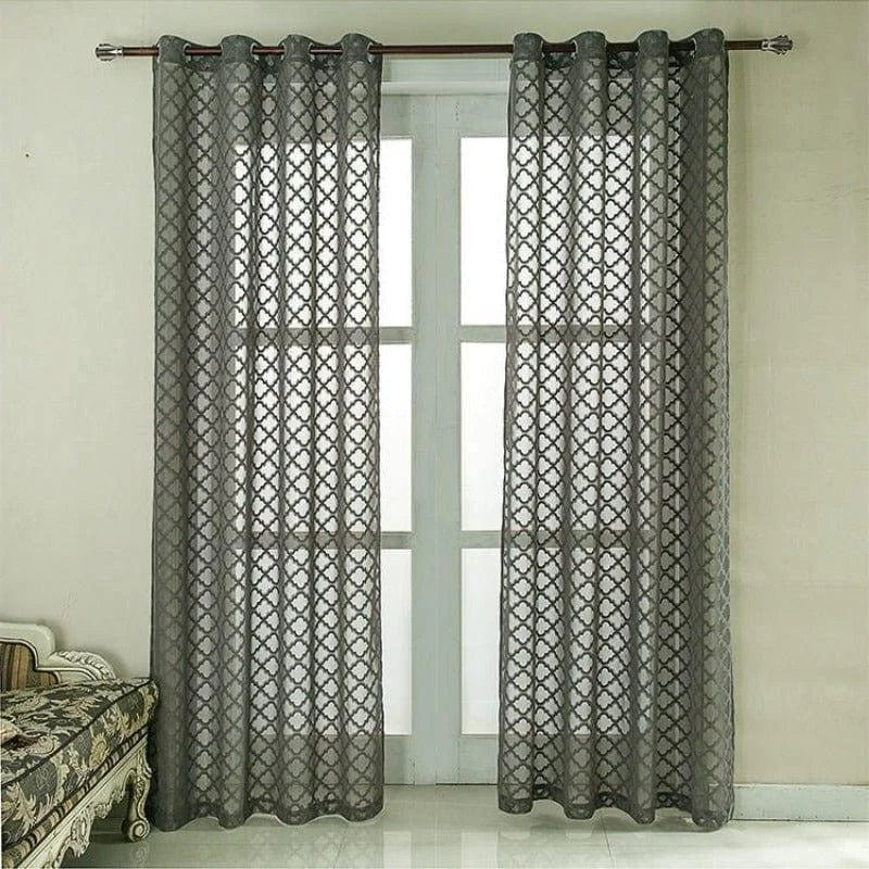 Rideaux gris à motifs géométriques suspendus devant une grande fenêtre, apportant une touche élégante et moderne à la décoration intérieure.