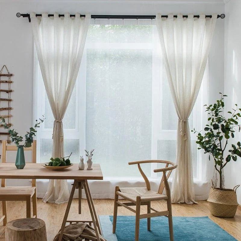 Salle à manger moderne avec rideaux blancs élégants, table en bois clair, chaises design et décoration naturelle, ambiance lumineuse et contemporaine.