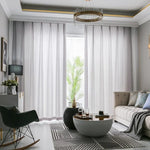 Salon moderne avec rideaux longs et légers laissant passer la lumière naturelle, complété par un canapé confortable et une table basse design, créant une ambiance élégante et accueillante. Décoration raffinée avec un tapis à motifs géométriques et des éléments de décoration contemporains, parfaits pour un intérieur sophistiqué.
